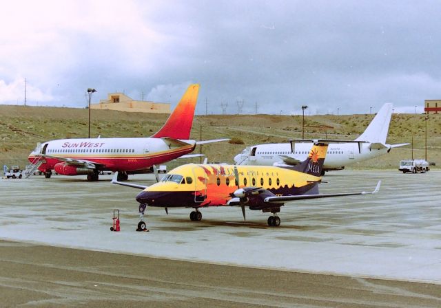 Beechcraft 1900 (N104YV) - KIFP - early morning March mid 1990s at Laughlin Bullhead City Airport - MESA Beech 1900 starting to wake up for the flight to Phoenix. The Sunwest 737-200 N705S was being readied for ATL-Atlanta GA if I remember correctly and the Casino Express Boeing 737-200 N233TM did not leave for several more hours. Photo from the Luggage rack( yes, I was able to stand atop the unit for this picture - (the Airport Mgr at the time saw me earlier and said it was OK to get photos from that vantage point!)