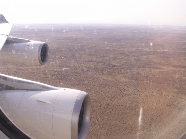 Airbus A340-300 (V5-NME) - Coming in a wonderful flat descend in to rwy 26R WDH in the morning of 10.09.2009 to the beginning of my first Namibia visit. On the left hand side, the B6 must be anywhere. Photo made from my seat 10A inside A340-300 V5-NME, which is stored meanwhile, as V5-NMF is. Both are replaced with A330-200 V5-ANO and V5-ANP in 2012.