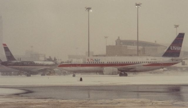 BOEING 737-300 (N515AU) - Not the best conditions for photography-sorry for the result. The big puddle is type 1 and type 4 deicing fluid out at the deice pad. Another day of typical winter ops at BOS -about 2001.