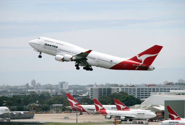 Boeing 747-400 (VH-OEI) - A 744 climbs out with more Qantas jumbos in the background: 744s and A380s.