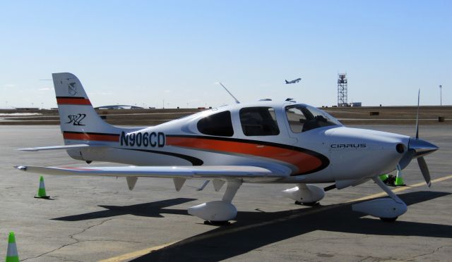 Cirrus SR-22 (N906CD) - Interesting paint design! Don't see orange every day! Taken at the FBO with a JetBlue E190 departing in the background!