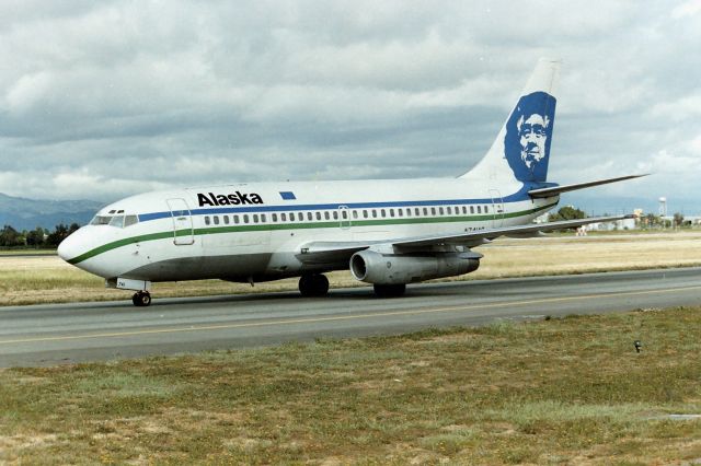 Boeing 737-200 (N741AS) - KSJC - apprx June 1987/88 while the new Terminal A was being built at San Jose,- the long term parking lot was moved out on the tarmac and fenced off. I immediately started using the lot with my pick up truck and ladder in the back bed, parking 3-5 rows back to beat the nosey Cops. I had very little interference here taking photos for the 3+ years it took to build terminal A - many days of the week out here filming, Cops would drive by and keep going. On this photo, Alaska 737-200 Combi was into San Jose most likely from Seattle or Portland and we saw this jet frequently along with N742AS sister ship, both running passengers - and I also saw this jet or 742AS at SFO sometimes when filming there. Taxi by here for Terminal C on a mid morning arrival at San Jose.