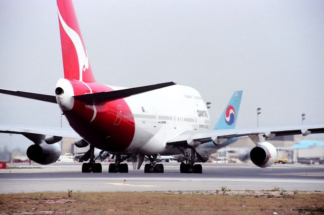 Boeing 747-400 (VH-OJE) - KLAX - QANTAS holding short 25R at LAX awaiting instruction to cross the active and taxi via the chute" to the north complex terminals.photo apprx Sept 1990.br /br /CN number 24482 LN:765br /Type 747-438br /First flight date 05/01/1990br /Test registration ??br /Seat configuration C56 W40 Y275 