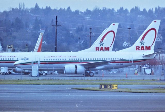 Boeing 737-700 (CN-RNQ) - KBFI - April 2000 on a cloudy day ramp at Boeing Seattle - -RNQ with a new -800 behind it undergoing final adjustments before delivery to Royal Air Maroc. Boeing 737-700  28985 LN:501 at the south-end of Boeing Field .