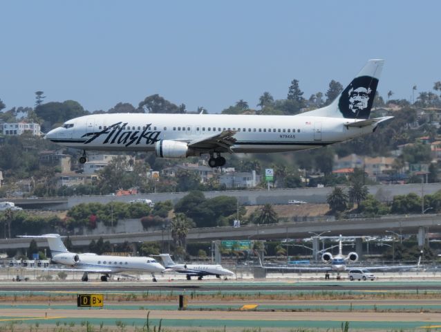 BOEING 737-400 (N794AS) - An Alaska 737-400 comes in fro touchdown @ SAN. Captures over some private jets on the tarmac near the Landmark Aviation Hangar.