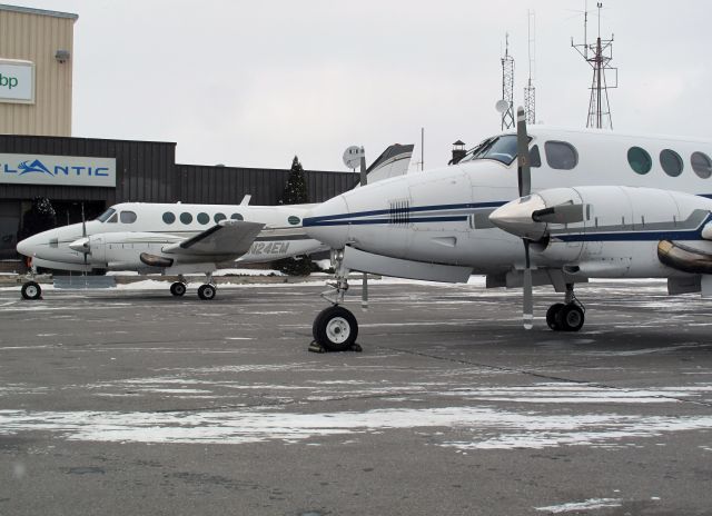 Beechcraft King Air 100 (N24EM) - Two King Air 100s parked next to each other.