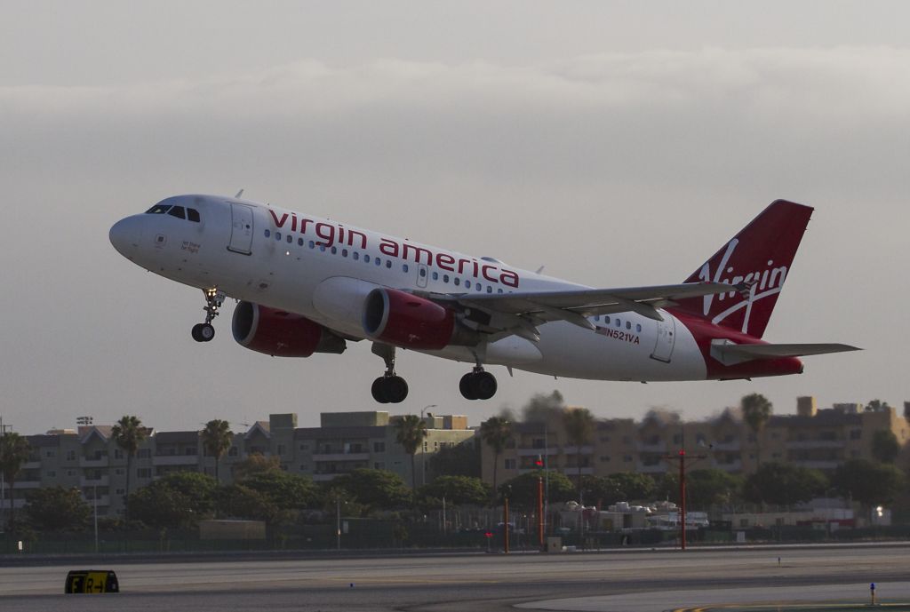 Airbus A319 (N521VA) - This Airbus A319 has Let There Be Flight painted under the pilots window. It is taking off early in the morning from runway 24L, LAX, Los Angeles International Airport.