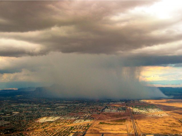 — — - A microburst from the air over Apache Junction AZ just east of Mesa. Look closely and on the left you can see the north end of the Superstition Mountains just behind the rainfall.