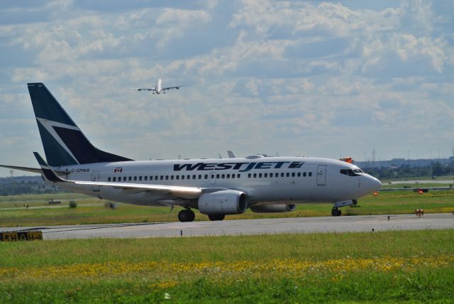 Boeing 737-700 (C-GRWS) - WestJet 37 taxiing onto runway 23 with China Eastern A340-600 departing in the background