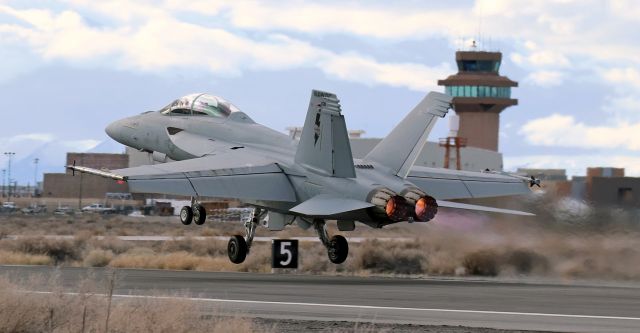 McDonnell Douglas FA-18 Hornet — - F/A-18E Super Hornetbr /A rare photo capture at NFL --- rare because departures from Runway 25-7 are extremely unusual. As we were told, the only time Runway 25-7 is utlized for takeoffs is when the wind shifts around and begins blowing increasingly strongly from the west, and when that occurs, the wind rapidly becomes so strong and gusty that, in the interest of safety, training sessions are soon suspended. As a result, no aircraft take off and after any aircraft that are already in the air are recovered, no more flying takes place.br /During our visit, the wind did shift and begin blowing from the west. And the wind speed did increase and become rather gusty. However, it never became strong enough to hurl sand, pebbles and tumbleweeds at us (which HAS happened during past visits), and training sorties continued to be flown. We relocated our spotting location to the intersection of Runways 31L-13R and 25-7 --- almost in the middle of the runway and taxiway layout --- and from that location it was possible to get the Control Tower in the background as the warbirds were rotating and starting to climb away from Runway 25.  95v / 5h