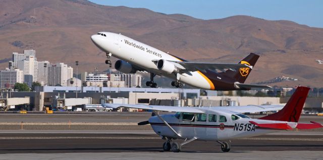 Airbus A300F4-600 (N143UP) - UPS's N143UP is off Runway 16R and beginning a steep climb away.  In the foreground, Red Tail's N51SA, a Cessna T207 Turbo Stationair, is parked on the Atlantic Aviation ramp awaiting another planeload of Burners (participants in the 2019 Burning Man festival in the Black Rock Desert).