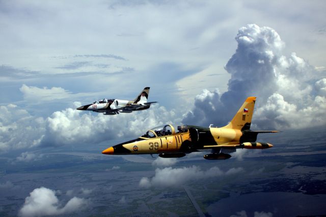 — — - Sonny Schilleci (foreground) with Mike Mosing in their two L-39s on a stormy day over the Mississippi River Delta south of New Orleans.  Photo by Lee Taylor.  Lancair 4 photo ship pilot was Carl McIntyre