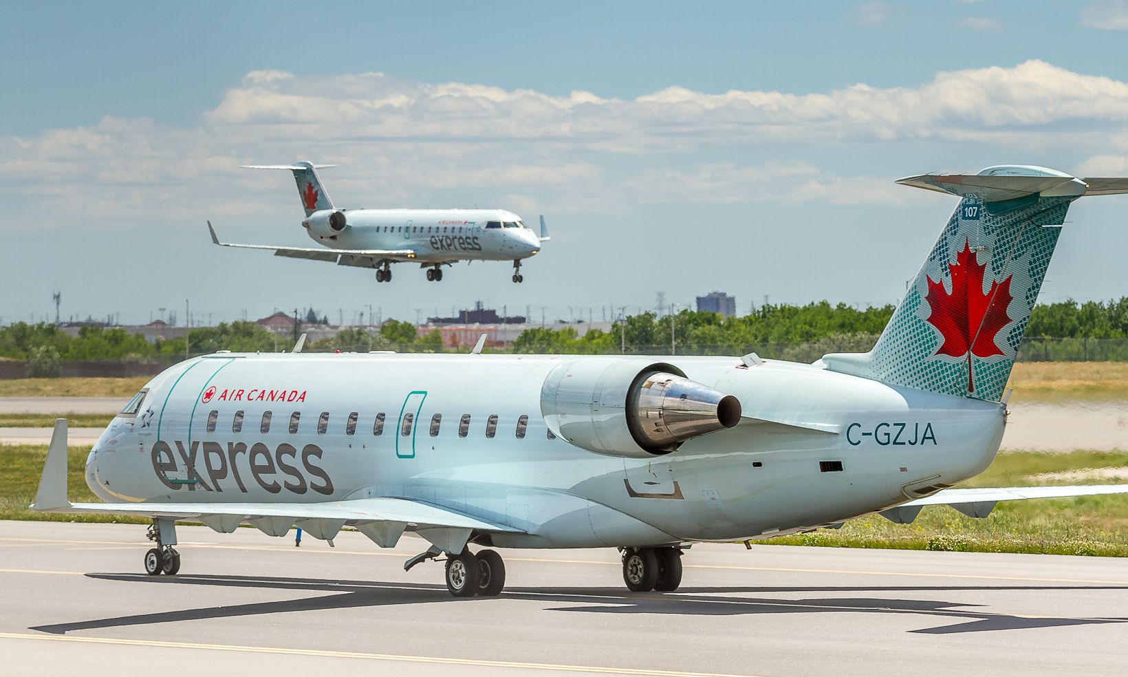 Canadair Regional Jet CRJ-200 (C-GZJA) - A company CRJ lands on runway 33L while this Air Georgian CRJ backtracks down the new taxiway and back to the terminal