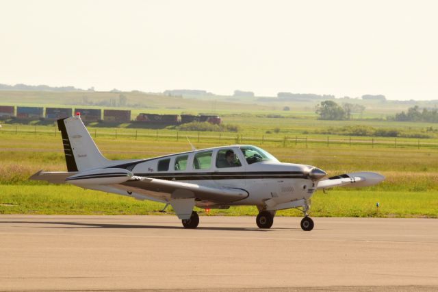 Beechcraft Bonanza (36) (C-GACG) - Beechcraft Bonanza 36 parking after arriving at YQV with CN train in the background. 