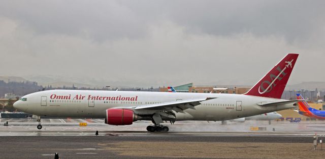 Boeing 777-200 (N819AX) - Beginning the thrust reversal process just as the nose wheel is about to kiss the wet concrete of runway 16R, OAEs N819AX arrives in Reno to pick up over 340 US Marines and take them back to Cherry Point, N. Carolina.  It was raining as this Triple 7 touched down, but by the time it departed, the rain had ended and the sun was finding ways to break thru the overcast.