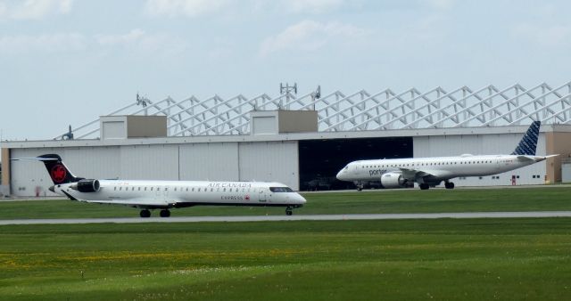 Canadair Regional Jet CRJ-900 (C-FJQZ) - Taxiing on the left is this 2021 Air Canada Express Mitsubishi Canadair Regional Jet 900LR with a Porter Embraer also heading to the terminal in the Spring of 2024.