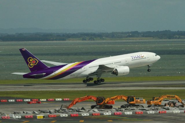 Boeing 777-200 (HS-TJS) - Part of the taxiway is under destruction as another B-777 lifts off.