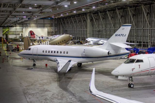 Dassault Falcon 2000 (N147CJ) - Domino's Pizza Falcon 2000LR sitting inside Hangar One along with the Yankee Air Museum's collection.