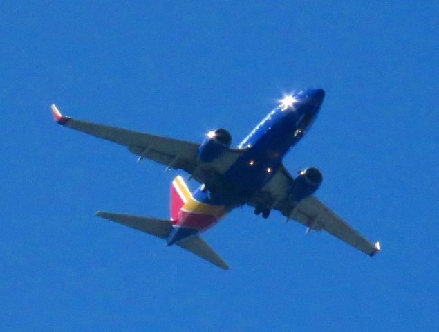 Boeing 737-700 — - Plane spotting from my back yard. Loved the sunburst from the front of the plane and the starboard engine. 