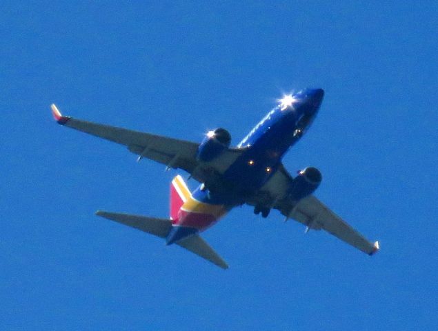 Boeing 737-700 — - Plane spotting from my back yard. Loved the sunburst from the front of the plane and the starboard engine. 