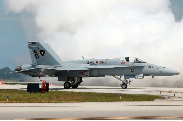 McDonnell Douglas FA-18 Hornet (16-3429) - A US Navy F/A-18C Hornet from Strike Fighter Squadron (VFA) 106, Gladiators, shadowed by smoke from the Shockwave at the 2016 Vero Beach Air Show on 26 June. The joint Marine/Navy demo team aircraft have Navy markings on the left-side and Marines on the right.