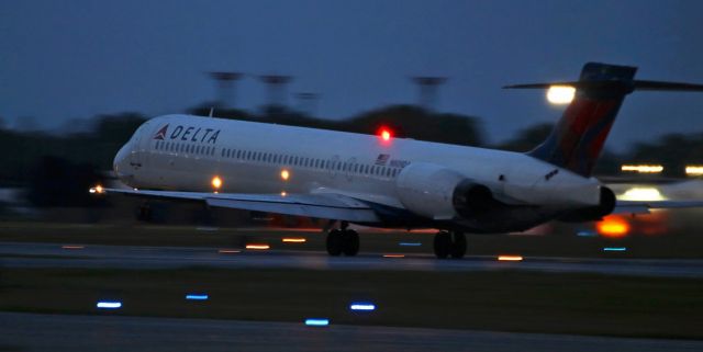 McDonnell Douglas MD-90 (N909DA) - One of the last photos of Delta's N909DA (MD-90-30) while it was still in active revenue service (**), this very early AM "break of dawn" click captured it at Vr speed as it became airborne and began its first flight of a new business day.br /I had expected this to pivot skyward much earlier so I had positioned about a third of the way down Runway 23, but the farther away down the runway this one went, the more difficult it was to maintain a steady panning motion with it and the more certain I was that by the time it finally did begin to rotate I'd end up with zilch. By the time I saw the nose gear come off the concrete it was quite far from me and awfully dark in my viewfinder. However, since I had gotten up in the darkness in order to be at the airport when the first hint of dawn appeared in the sky, I had already invested enough time that I was not going to give up and discontinue snapping the shutter. And I got lucky -- my panning was steady, my slower shutter still caught the Dog crisply, and I got what turned out to be my last-ever photo of a Delta Mad Dog in rotation toward the sky. If I had it to do all over again, I dang sure would!!br /** Just over three months after this shot was snapped, N909DA was wfu and went into storage at MMQT.