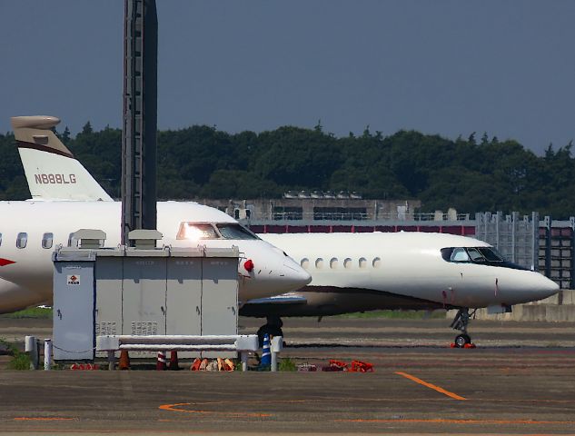 Dassault Falcon 900 (N888LG) - I took this picture on Aug 02, 2018.br /The N888LG can't get the whole picture because of the other planes and lighting facilities in the foreground. In addition, the strong summer sunshine produced a sun flame, which resulted in a poor image quality.