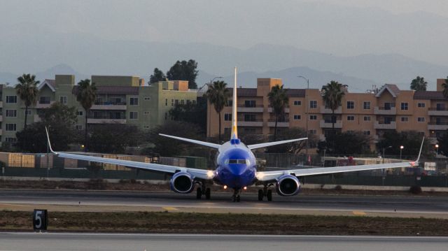 Boeing 737-700 (N77338) - This Boeing 737 has just landed in the early morning light, it is hooking around to the left to use taxiway Yankee to cross runway 24L at Los Angeles, California USA.