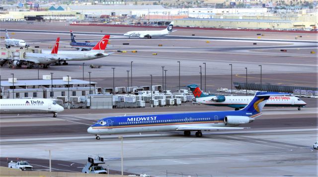 McDonnell Douglas MD-82 (N810ME) - KPHX - Mar 2007 view from atop the parking garage. While on a driving tour to Phoenix area visiting elderly relatives, I'd always stop by PHX for some great air photos - and this day was real good. 2 items of note, and from 2014-2015 I lived right near Monterey Regional Airport and the wife and I flew the MRY-PHX nonstop to visit again and we flew on the America West Express CRJ-900 shown here but in US Airways colors on N928LR. I also have photos of this jet landing at MRY in AWE colors when I lived nearby. Another item, Ive worked for the same Company 43 years and when I transferred back up to the RDD area office in late 2015, a new hire I met there used to work for Northwest Airlines at PHX, and was most likely working this day when I took this. I usually never went inside the terminals to film, so I was always at the best vantage points outside. He worked gate 23 often he said. The Delta peeking in from the left in MD-90 N913DN? Off to my right out of view is the America West Ramp I'll post one later, I think every gate is full so the picture is massive jets at the gates, pre summer so it was only about 75 degrees,,,I cant imagine working PHX ramp in the summer.