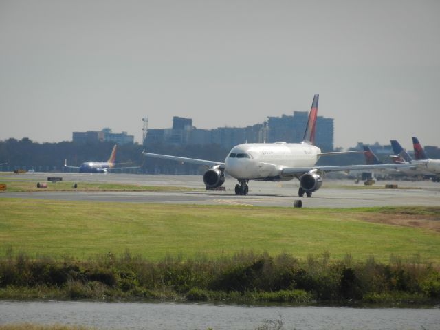 Airbus A320 (N356NW) - N356NW, A Airbus A320 Of Delta Airlines, Holding Short On A Taxiway. On The Right Side Are Two Delta Tails And One United Tail, In The Distance A Southwest Airlines Boeing 737-700 Is Taxiing To The Runway.