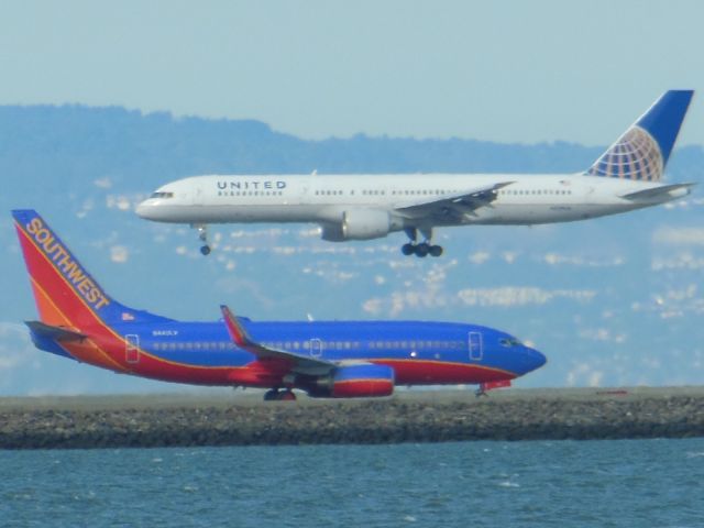 Boeing 757-200 — - United 757 landing as Southwest 737 taxis for takeoff on 28L