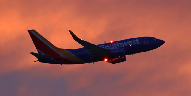 Boeing 737-700 (N493WN) - Southwest's N493WN on the climb during a very early morning departure for OAK. This blazing morning sunrise light only lasted about 8 or 9 minutes before it rapidly faded away and the brilliant sunlight shining directly into the lens forced me to reposition to the east side of the airport so the sun was at my back.