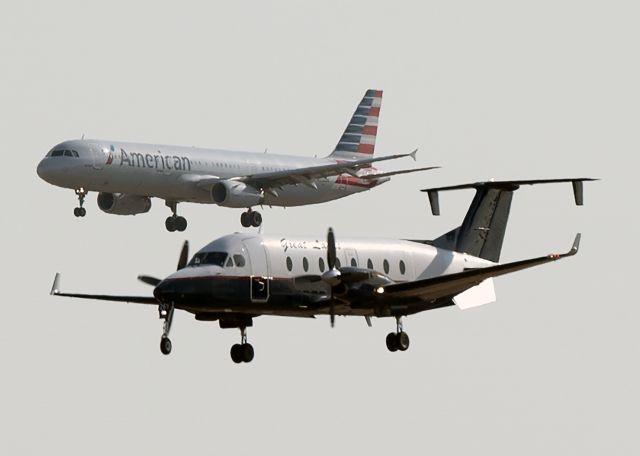 Beechcraft 1900 (N261GL) - Not the best shot. The B1900 is landing on 25R while the AA A321 is landing on 26. 