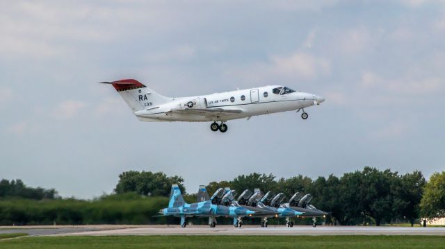 Beechcraft Beechjet (N92331) - T-1A Jayhawk comes into RND a bit slow and nose high, later photos in the sequence would show an extreme flare angle similar to that of the T-38s in the background