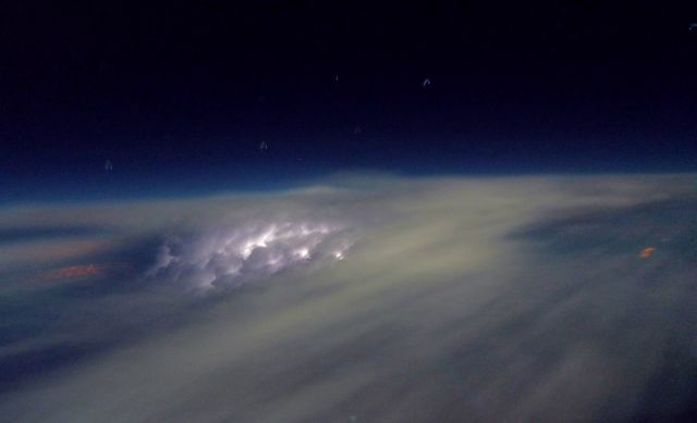 — — - Long exposure at FL430 captures lighting in a line of thunderstorms below us.