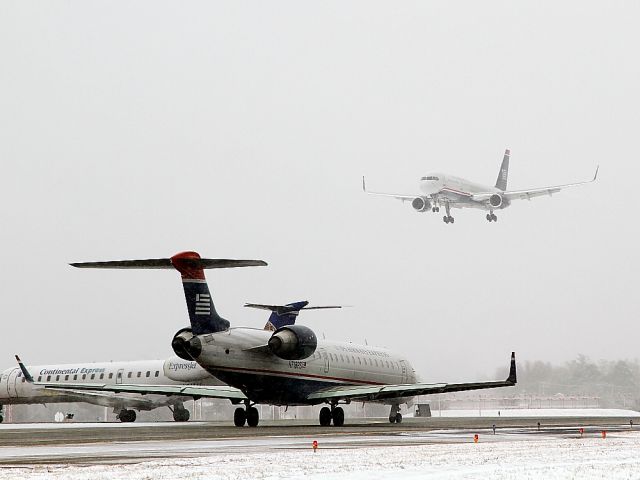 Boeing 757-200 (N202UW) - Two regional jets wait patiently while a US Airways Boeing 757 breaks through low clouds and light snow to land on runway 36R at Charlotte, North Carolina, USA. (photo taken on Sunday, 26 December 2010)