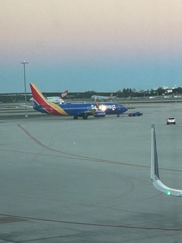 Boeing 737-800 (N8559Q) - Southwest B737-800 under tow to terminal 1 with the Virgin Orbit 747 background and American Airlines A321 rotating off of 28R/10L for Philadelphia