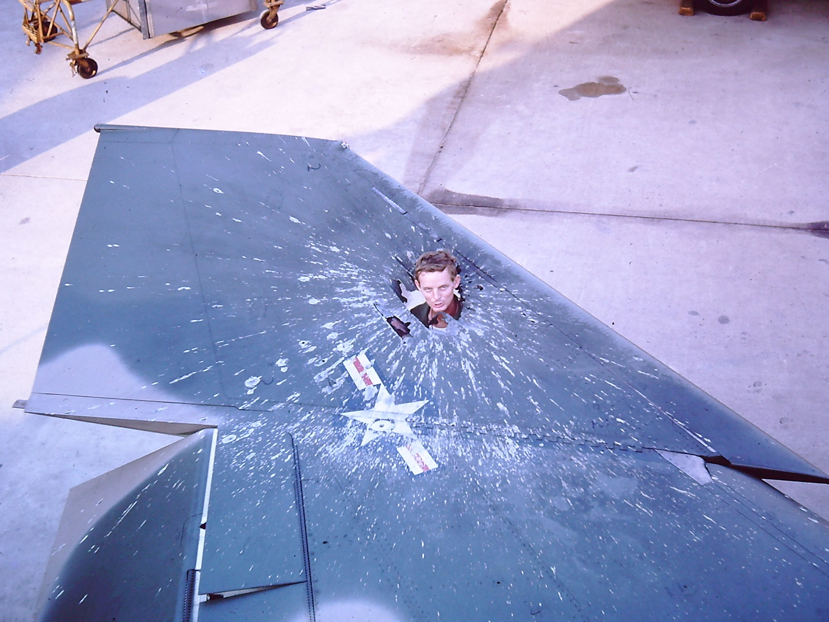 AFR41036 — - TAN SON NHUT AIR BASE, SAIGON, VIETNAM APRIL 1966 ATTACK ON THE base and the RF-4C squadron.  Attack was at night and this photo was late the next afternoon as one of the guys puts his head up through a direct hit on the wing to show the size of the hole.