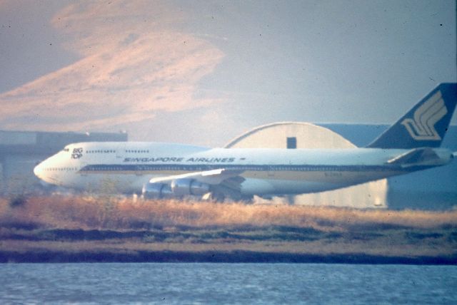 BOEING 747-300 (N124KK) - KSFO - 28L arrival for the Singapore 747-3 as the fog held off this day as the late PM sun angle from the west glints off San Bruno Mountain to the north. The photo late 1980s or early 90s. I super enlarged this photo to read the reg, showed as N124 but I couldnt read the letters, assuming KK. 1000mm Celestron lens - Minolta XD-11 from the dirt lots before Bayfront Park was built.