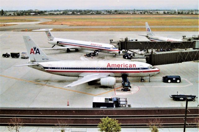 BOEING 737-300 (N677AA) - KSJC - early 1990s view from atop the parking structure looking west. New terminal A was opened early 1990s and the view from the parking structure was good and the railing wall side was perfect for balancing the video camera. Later US Air and Southwest worked the gates here, before SJC Officials built the US Customs building here and ruined the wide view. N677AA was originally Aircal N303AC when ordered new  and delv Dec 1985. Ln 1182.