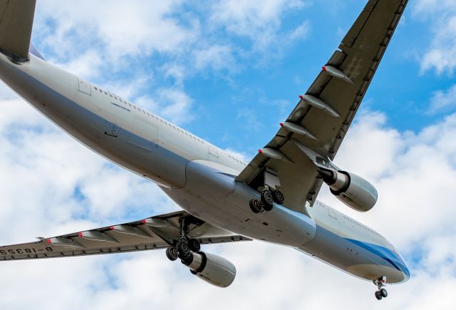 Airbus A330-300 (B-18359) - Photographed on short final for Runway 02 at about 300ft AGL, about to cross Ryans Road and the DVOR. The aircraft was holding about 10 drift to the left due to the westerly crosswind. The pilots didnt yaw right before touchdown, so the gear got a smokey hammering. Somewhat typical of non-local pilots.