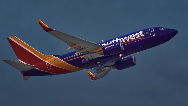 Boeing 737-700 (N7711N) - Shot before sunrise at ISO 6400.  The sunrise twilight colors showing in a narrow band between the horizon and the overcast and reflecting on the aircraft.