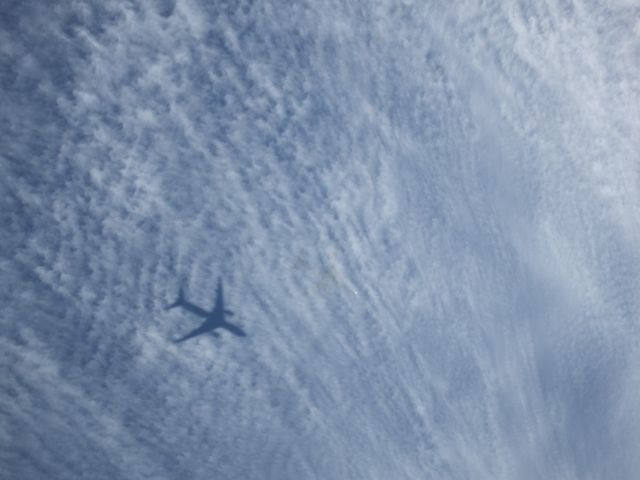 — — - This is Air New Zealand flight NZ80 from Shanghai near One Tree Hill just before a turn for final approach to Auckland Airport, on 16/12/2013. The shadow of the B777-200 – ZK-OKE is clearly seen on the thin cloud layer. The aircraft is to the right of the shadow with small bright spot being a reflection of the sun on the nose of the aircraft.