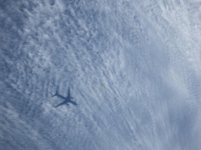 — — - This is Air New Zealand flight NZ80 from Shanghai near One Tree Hill just before a turn for final approach to Auckland Airport, on 16/12/2013. The shadow of the B777-200 – ZK-OKE is clearly seen on the thin cloud layer. The aircraft is to the right of the shadow with small bright spot being a reflection of the sun on the nose of the aircraft.