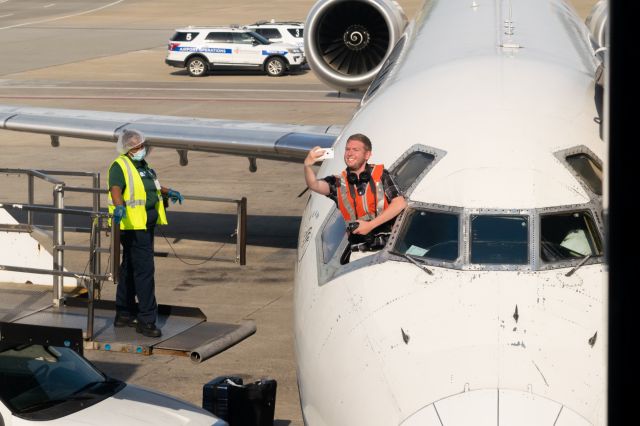 McDonnell Douglas MD-90 (N925DN) - Instagram personality Captain Cooper poses for a selfie with the last MD90 while a gate gourmet worker wonders why this man is sticking his head out the window.