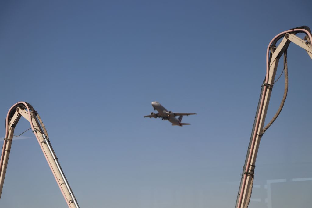 Airbus A319 (N654AW) - 6/19/18 departing PHX between the arms of the jet bridge