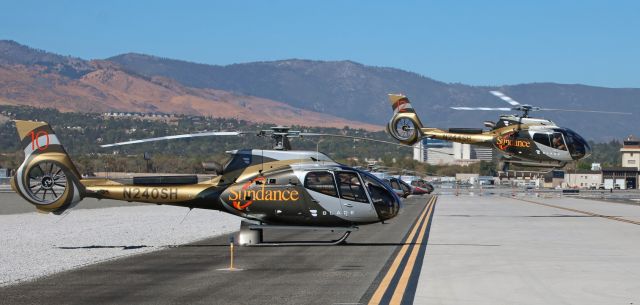 Eurocopter EC-130 (N240SH) - These two Airbus helicopters are two of the many helicopters flying people from all around the world out to the Black Rock Desert where the annual Burning Man Festival is in progress. In this photo (best viewed by clicking on FULL), Sundances N244SH is lifting away from Lima taxiway to make the fourteen minute trip from RNO to the temporary airport (88NV-- see ** below) in the Black Rock Desert while N240SH awaits its next load of passengers. In the background, N878MH is one of four Maverick Helicopters EC30s also flying people to the festival. And just as an "interesting" bit of additional information -- the fare for the quarter-hour flight to get to the festival is (are you ready for this?) .... waaaay over $2000.00 per person. But it is well worth the price. People who drove out were waiting in line for over 15 hours to get in ... and that was AFTER they made the two-hour drive from Reno to Gerlach. Tonight, the Man will burn, and then about 80,000 attendees will all start leaving. And these helicopters will be busy again.br /** The airport in the Black Rock Desert is a temporary strip which is established each year just to accommodate helicopters and small passenger planes that bring attendees from RNO to the festival. It even has a very small control tower that is built to direct the air traffic. The airport is assigned an identification number, 88NV. And every year, after the festival is concluded and as required by the Bureau of Land Management, the airport must be dismantled so completely that no remnants of it are left behind. 