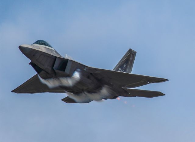 Lockheed F-22 Raptor — - F-22 performing a high speed pass over the airfield with a vapor cloud forming underneath. What an awesome airplane! Questions about this photo can be sent to Info@FlewShots.com