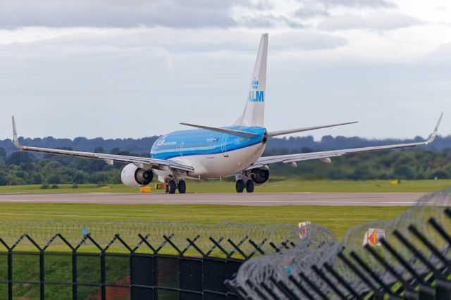 Boeing 737-700 (PH-BGP) - The southside perimeter fence frames this shot of KLM1074 rolling on the early morning flight back to Amsterdam