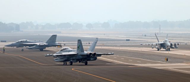 McDonnell Douglas FA-18 Hornet (16-8937) - Diverted from NAS Fallon, a trio of VAQ-135 "Black Ravens" E/A-18G Growlers (NAS Whidbey Island) is being marshaled into parking positions right on the Atlantic Aviation taxiway. The Growlers had to taxi directly on to the RNO motor vehicle perimeter road surface in order to be able to turn left and park on Atlantics taxiway. The Atlantic taxiway had to be utilized as a parking ramp when military aircraft from KNFL were diverted to Reno at the same time that numerous Air Tankers involved in fighting many wildfires in California were also diverted to Reno. When the many extra aircraft were added to the number of aircraft already at Atlantic, the regular ramp became completely full; therefore, more aircraft parking positions were improvised by quick-thinking Atlantic management and ground personnel. In this pic, the "Black Ravens" Squadron colorbird, 168937, "Thunder One One," turns toward the motor vehicle perimeter road where it will proceed forward and then turn to be parked next to another "Black Ravens" Growler (168940).